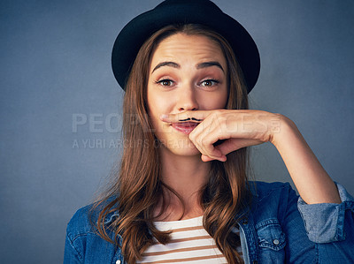 Buy stock photo Shot of a comical young woman posing with a mustache drawn on her finger in studio