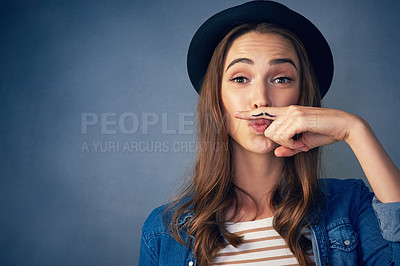 Buy stock photo Shot of a comical young woman posing with a mustache drawn on her finger in studio