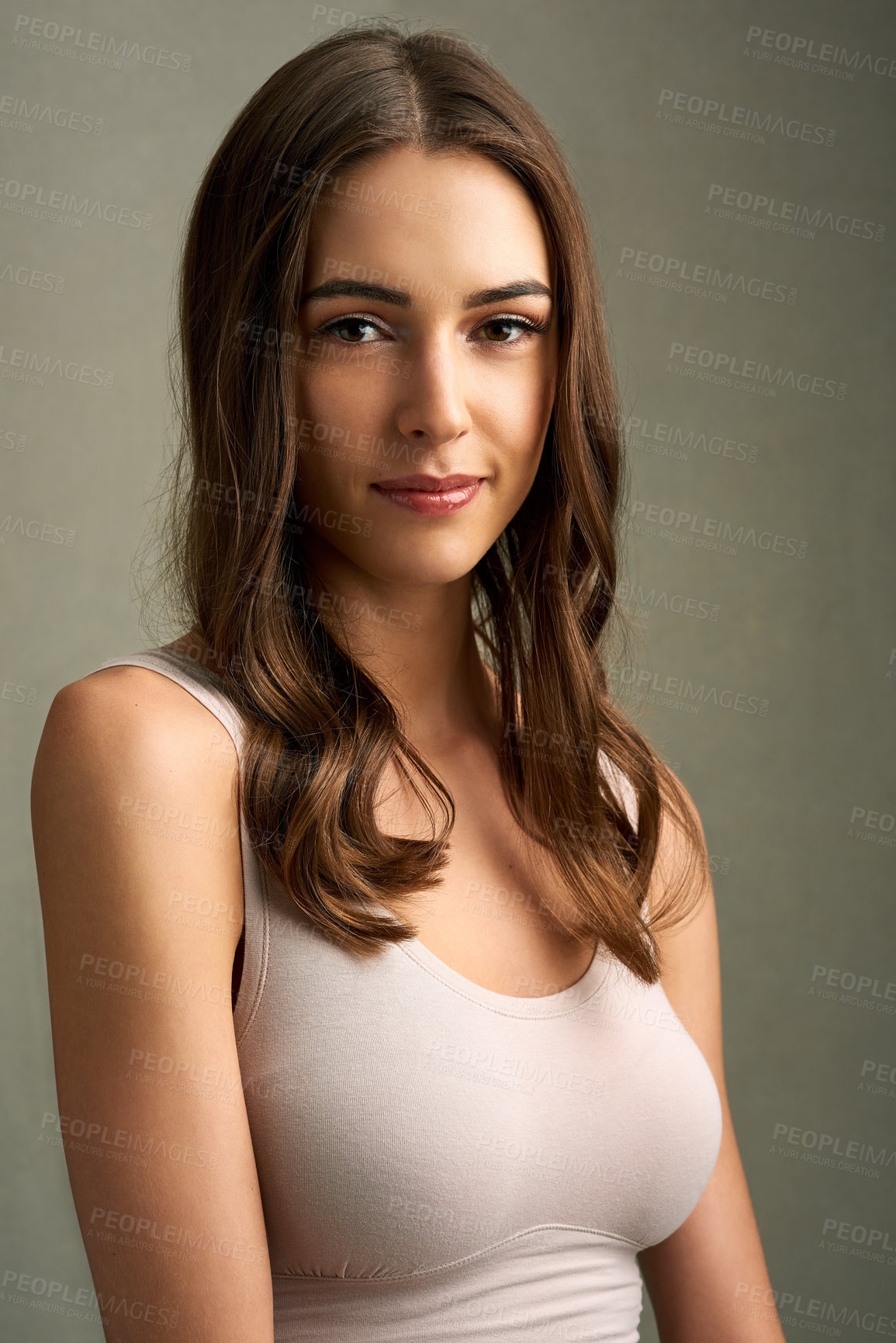 Buy stock photo Studio portrait of an attractive young woman standing against a brown background