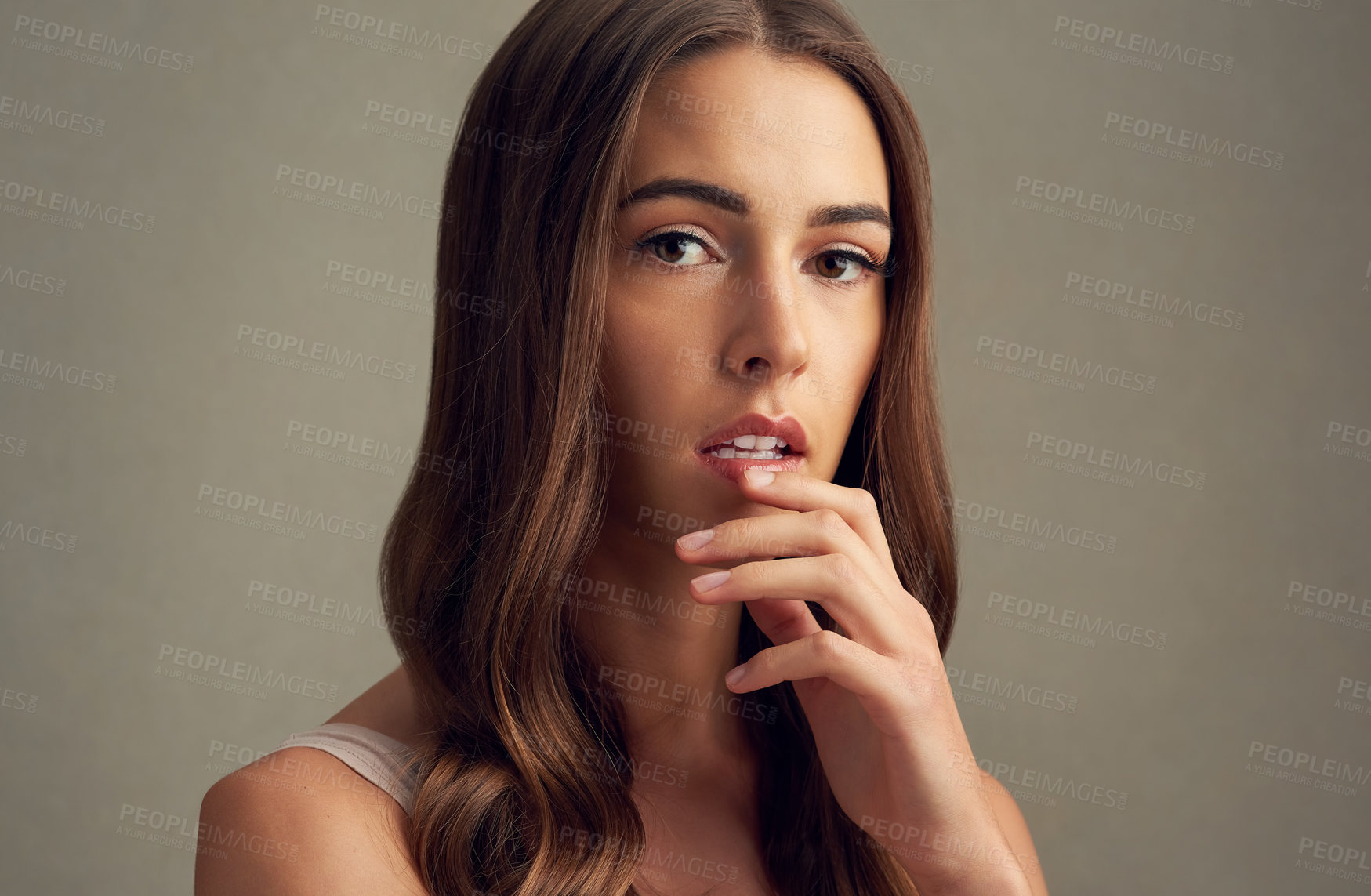 Buy stock photo Studio portrait of an attractive young woman standing against a brown background