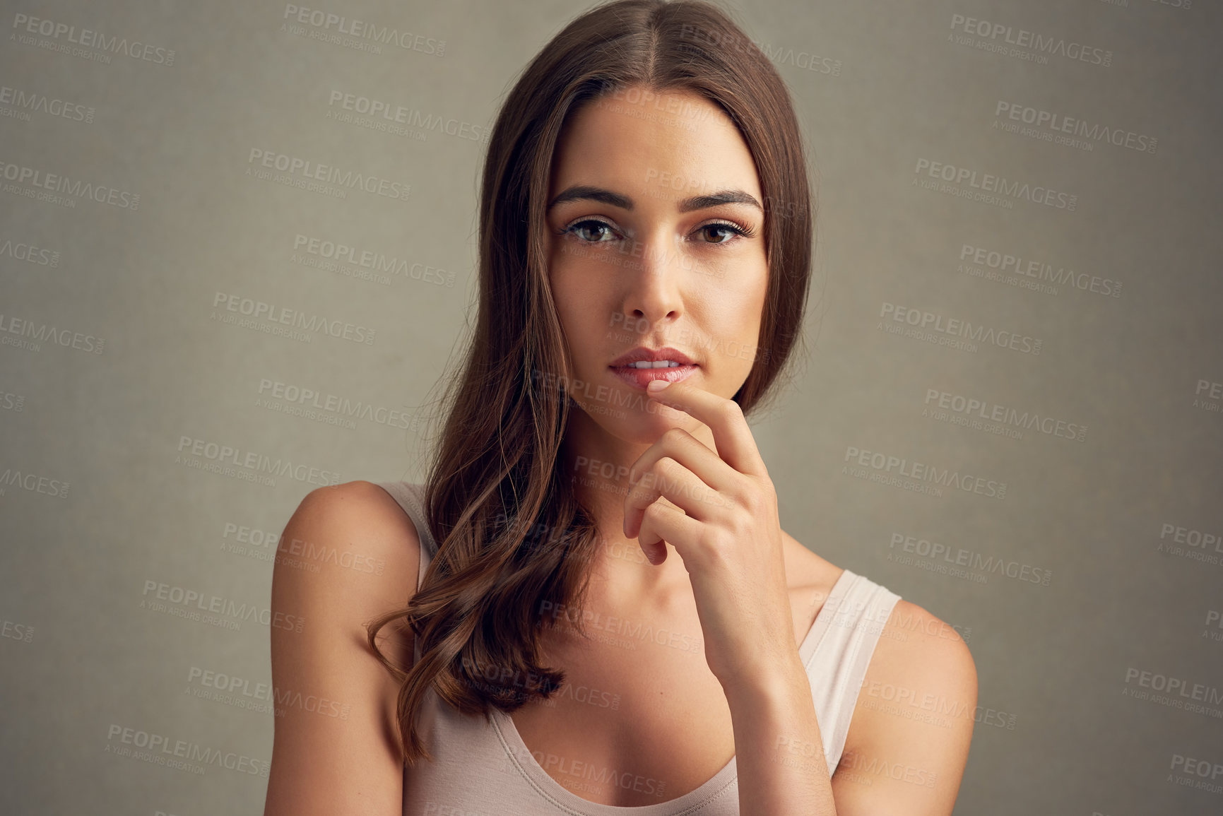 Buy stock photo Studio portrait of an attractive young woman standing against a brown background