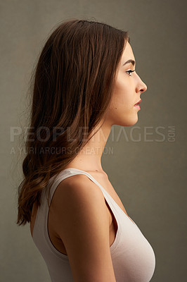 Buy stock photo Studio profile of an attractive young woman standing against a brown background