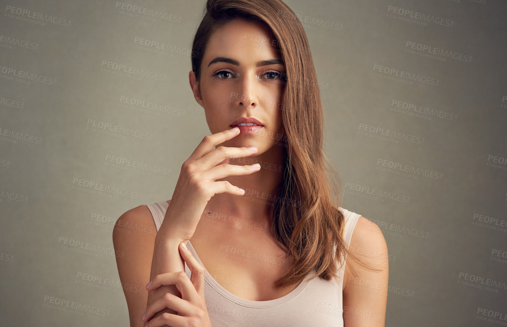 Buy stock photo Studio portrait of an attractive young woman standing against a brown background