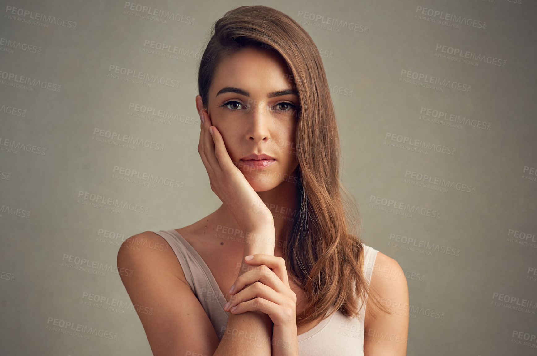 Buy stock photo Studio portrait of an attractive young woman standing against a brown background