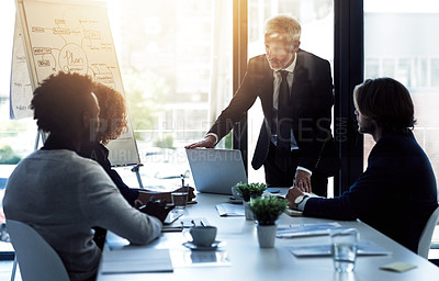 Buy stock photo Shot of a mature businessman giving a presentation to colleagues in a boardroom