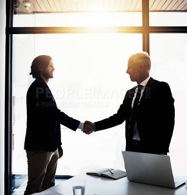 Buy stock photo Shot of two business colleagues shaking hands together in a boardroom