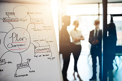 Buy stock photo Shot of business notes on a whiteboard with colleagues standing in the background