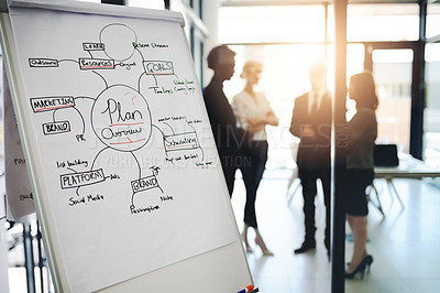 Buy stock photo Shot of business notes on a whiteboard with colleagues standing in the background