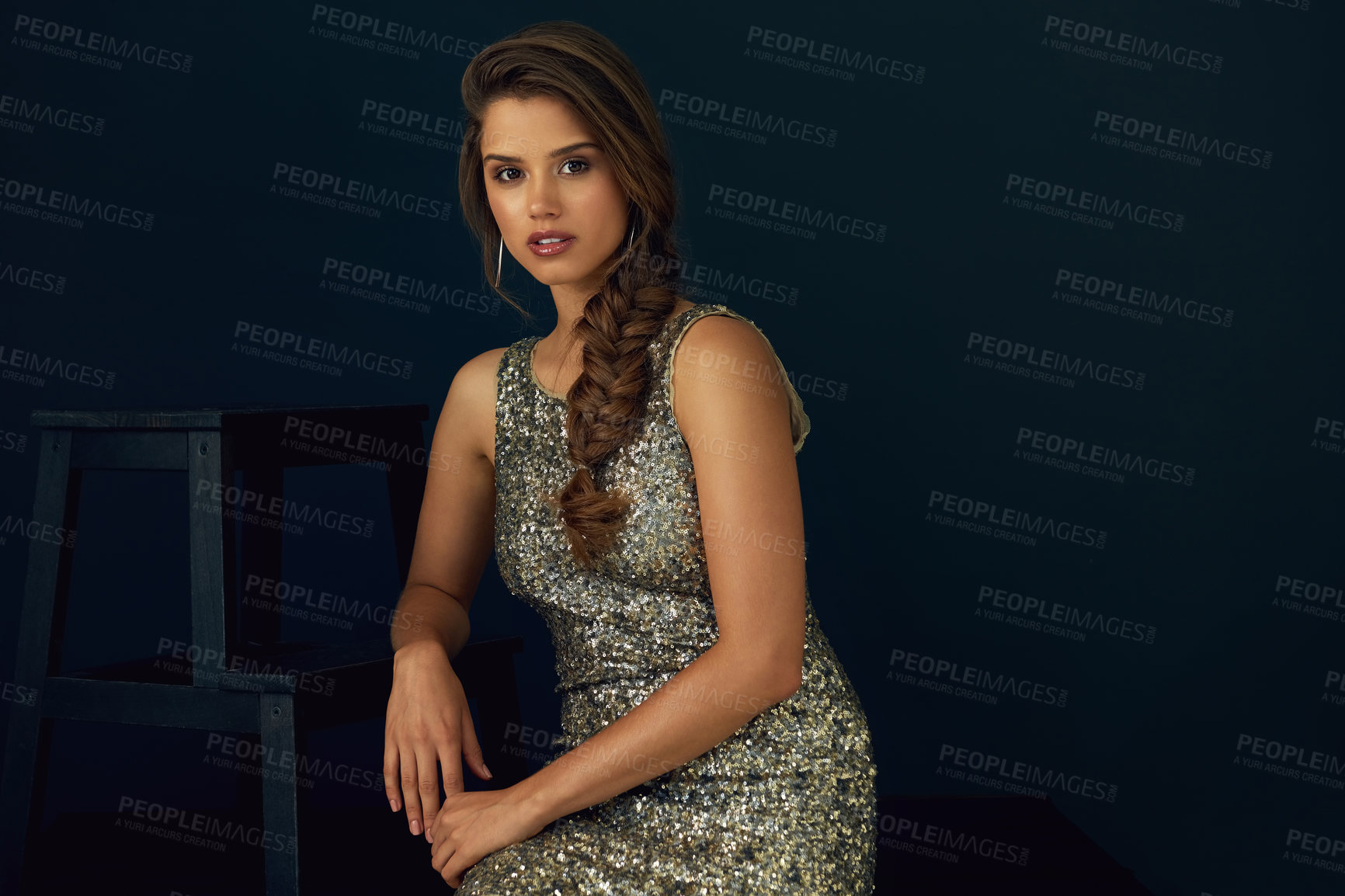 Buy stock photo Portrait of a beautiful young woman in a sequined dress posing against a dark background