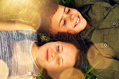 Buy stock photo Shot of two cute siblings lying side by side on the grass outside