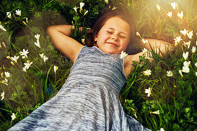 Buy stock photo Shot of a cute little girl lying in a field of wildflowers outside