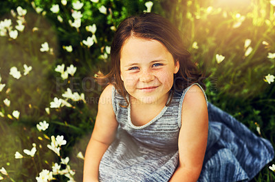 Buy stock photo Portrait of a sweet little girl sitting in a field of wildflowers