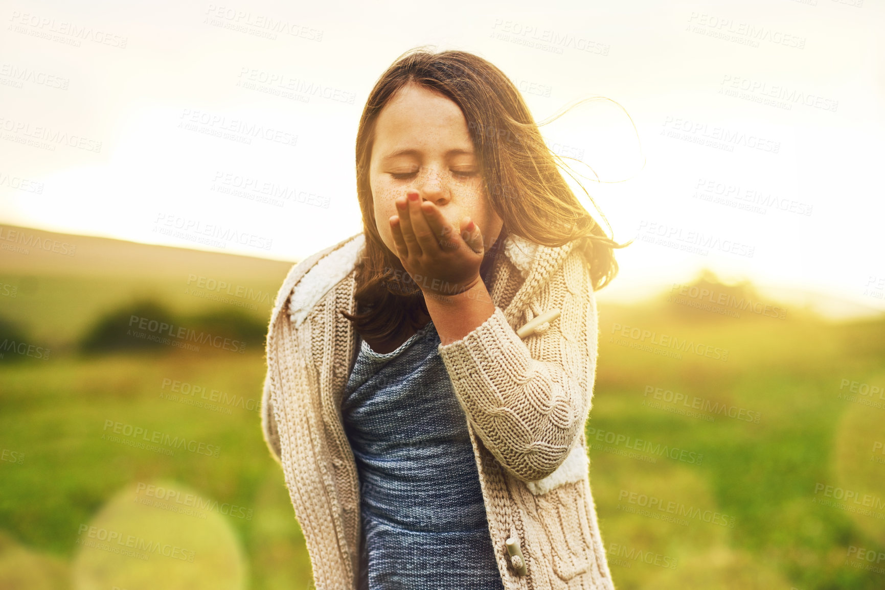 Buy stock photo Portrait of a sweet little girl blowing a kiss while standing outside