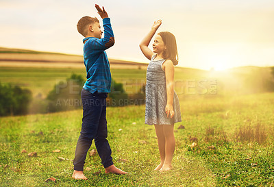 Buy stock photo Shot of a cute brother and sister high fiving each other while playing outside