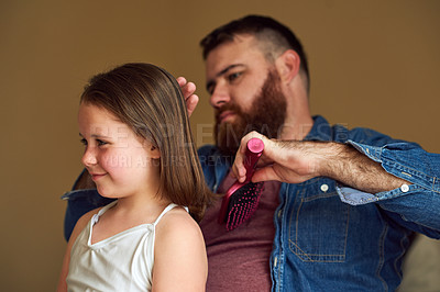 Buy stock photo Shot of a father brushing his daughter’s hair at home