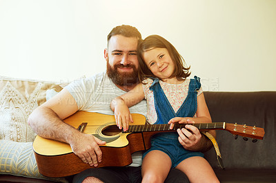 Buy stock photo Shot of an adorable little girl playing the guitar with her father at home