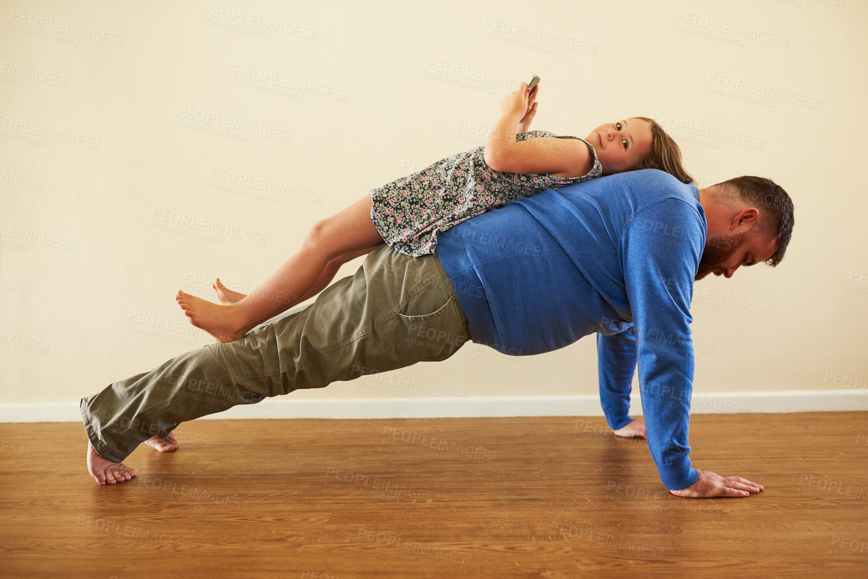 Buy stock photo Shot of an adorable little girl playing with a phone on her father’s back while he works out