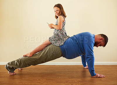 Buy stock photo Shot of an adorable little girl playing with a phone on her father’s back while he works out