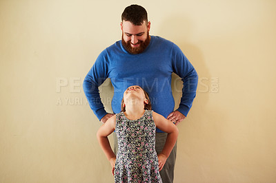 Buy stock photo Shot of a happy little girl girl standing in front of her father and looking up at home