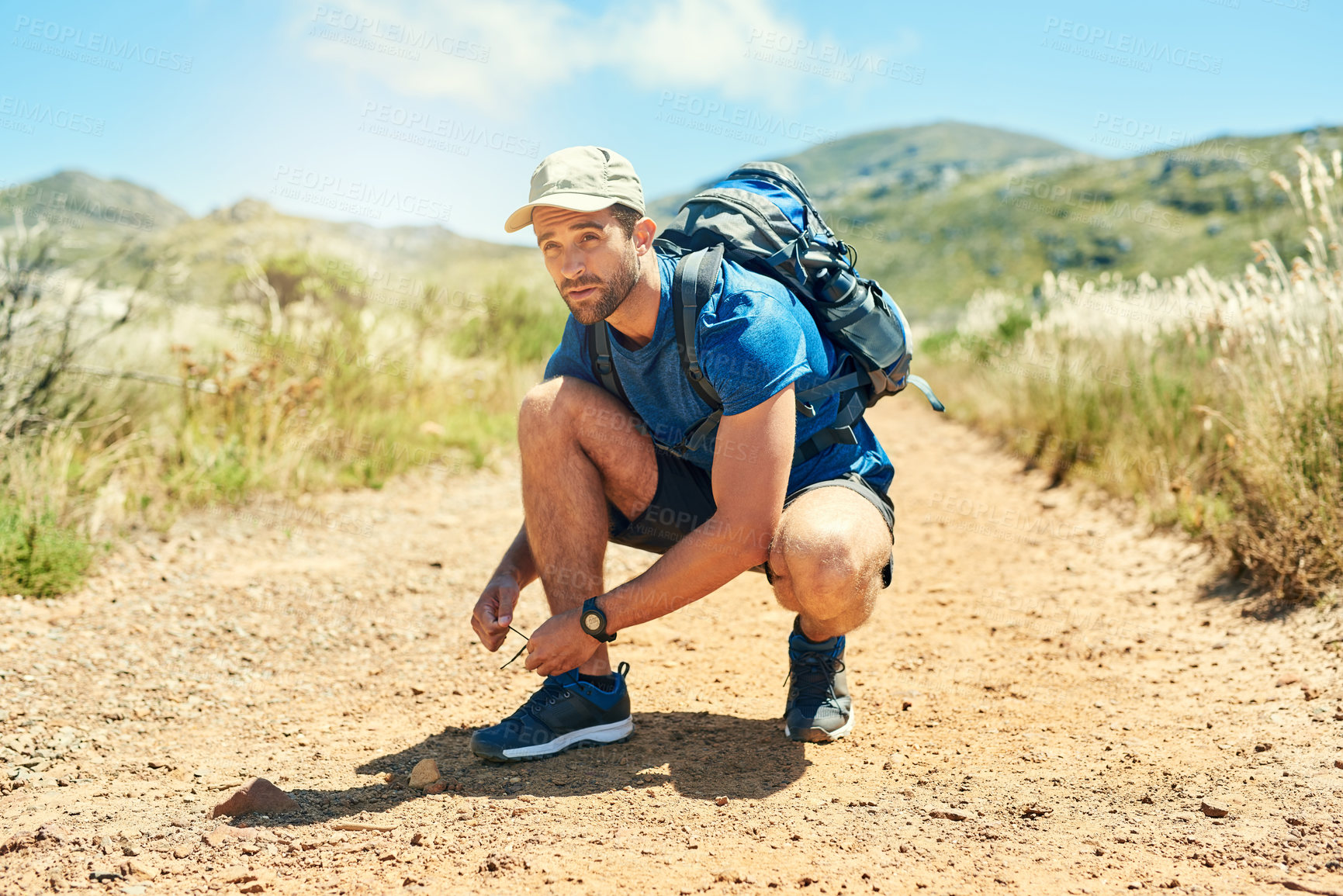 Buy stock photo Shot of a young man tying his shoelaces while out on a hike