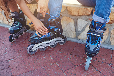 Buy stock photo Closeup shot of a woman helping her boyfriend putting on rollerblades in a park