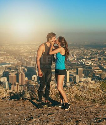 Buy stock photo Exercise, couple and kiss on mountain outdoor with city view, fitness and workout together for healthcare or affection. Man, woman and bonding with adventure in summer for hiking, nature and cardio.