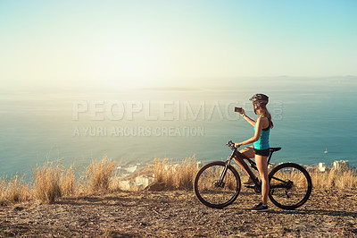 Buy stock photo Shot of a young woman taking a picture of the beautiful scenery while out mountain biking