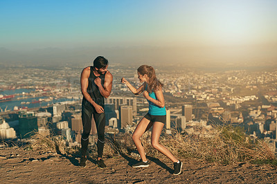 Buy stock photo Shot of a sporty couple being playful against a city background