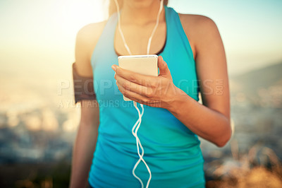 Buy stock photo Cropped shot of a young woman listening to music while out for a run
