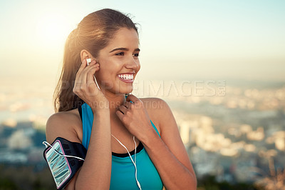 Buy stock photo Cropped shot of a young woman listening to music while out for a run