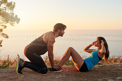 Buy stock photo Shot of a young man motivating his girlfriend while she's doing sit ups