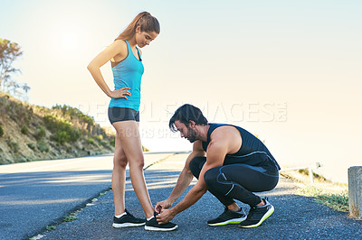 Buy stock photo Shot of a man typing his girlfriend's laces while out for a run