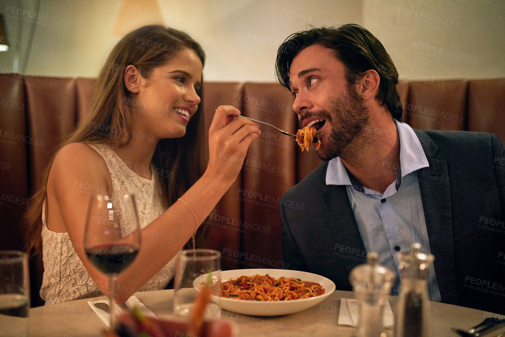 Buy stock photo Love, restaurant date and woman feeding man spaghetti on valentines day, happy and romantic dinner. Romance, valentine and food with wine, couple celebrate marriage or relationship with time together