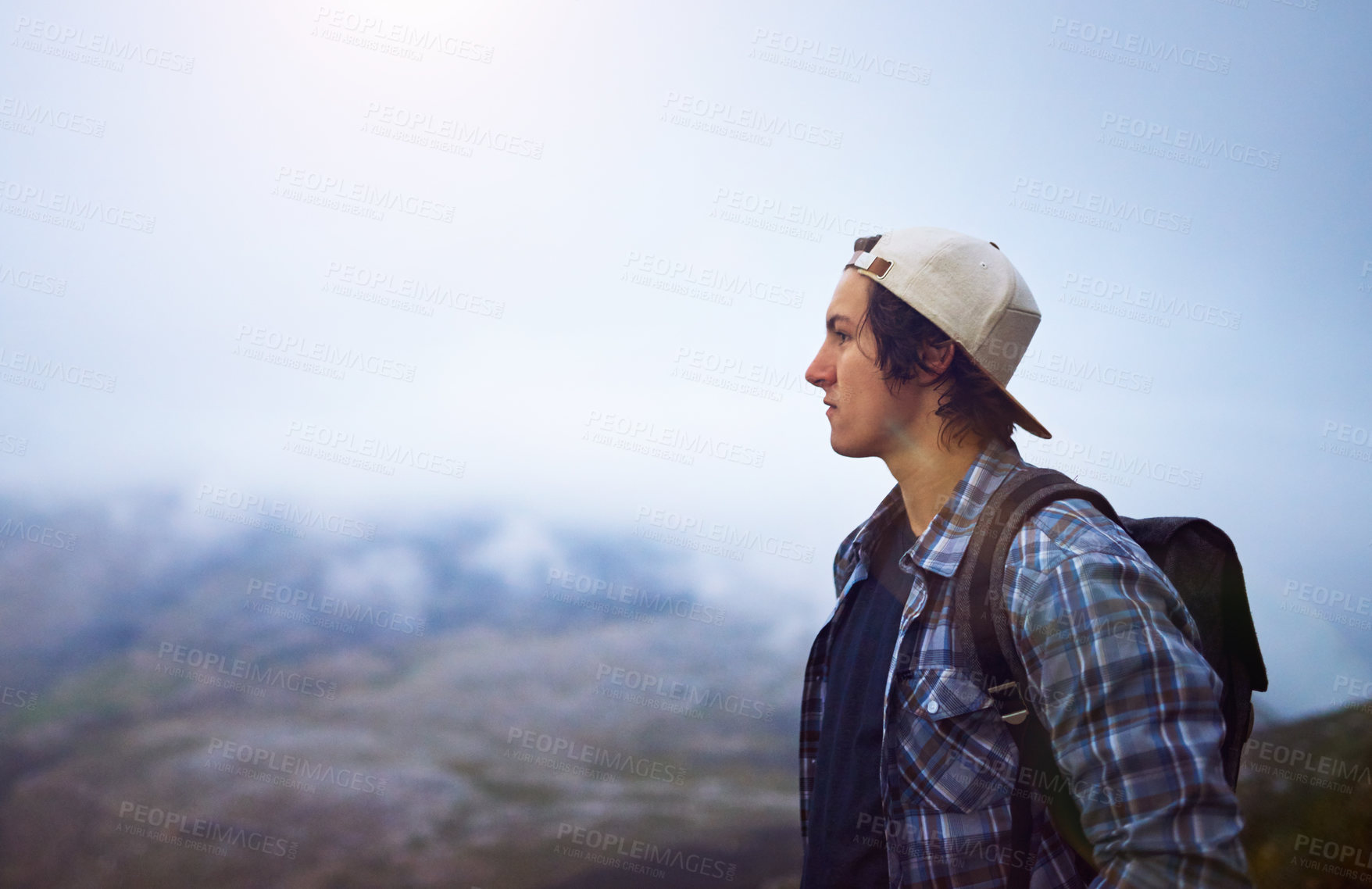 Buy stock photo Shot of a young hiker admiring a foggy view from the top of a mountain