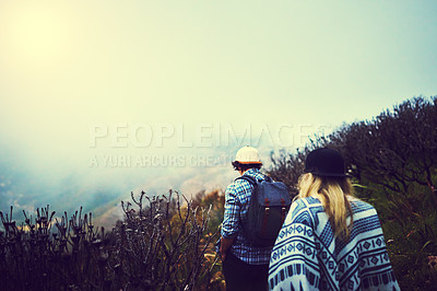 Buy stock photo Rearview shot of two unidentifiable young hikers walking along a mountain trail