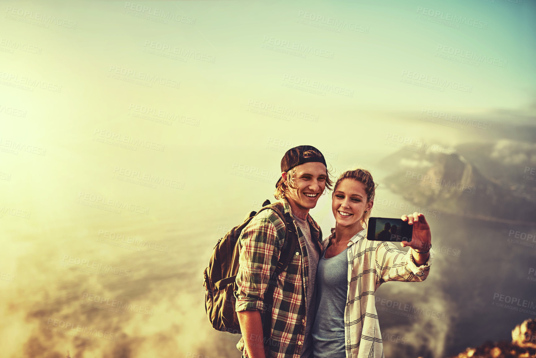 Buy stock photo Shot of a happy young couple posing for a selfie while out on a hike together