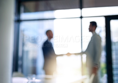 Buy stock photo Blurred shot of two businessmen shaking hands in a modern office