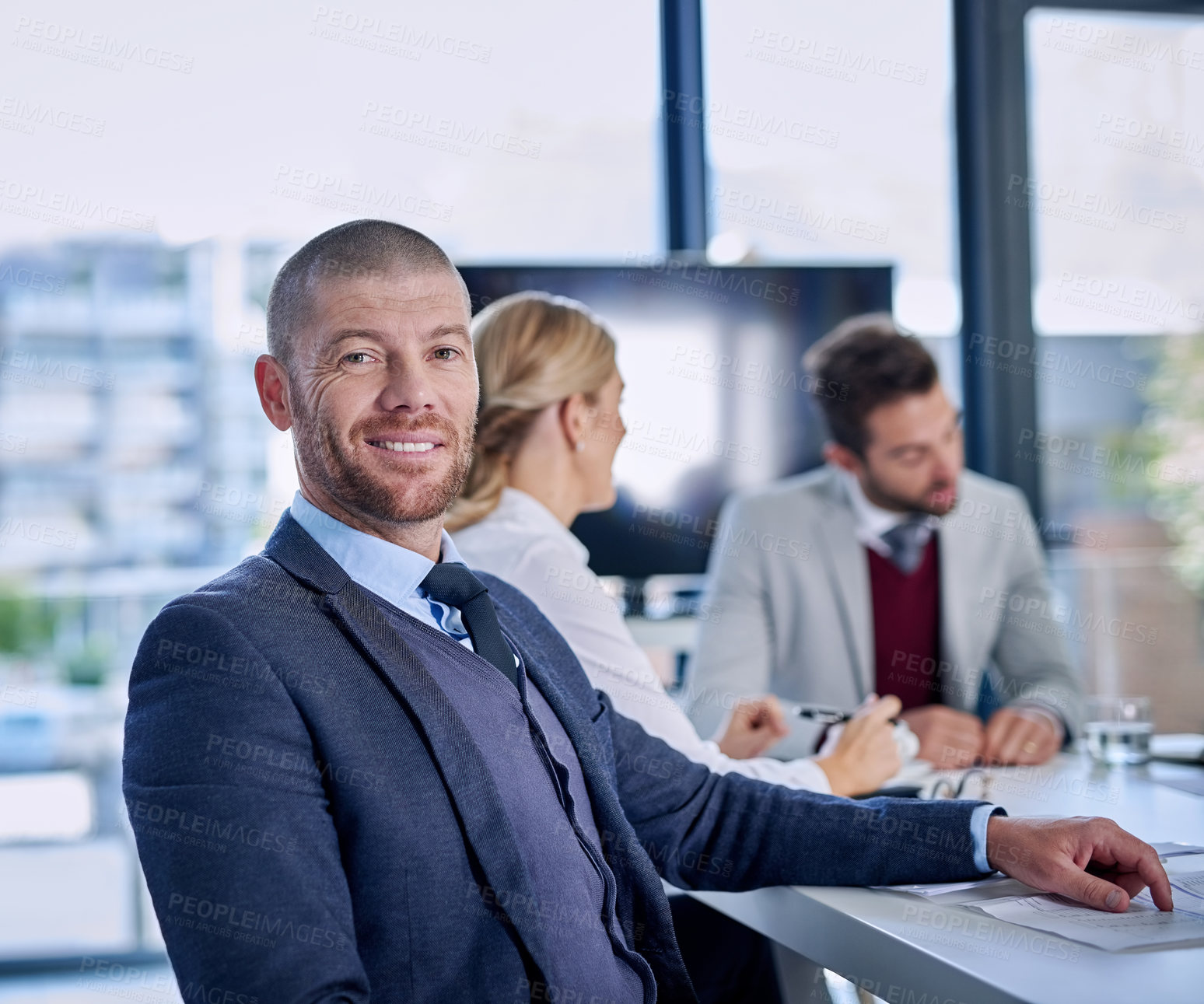 Buy stock photo Portrait of a businessman sitting in an office with his colleagues in the background