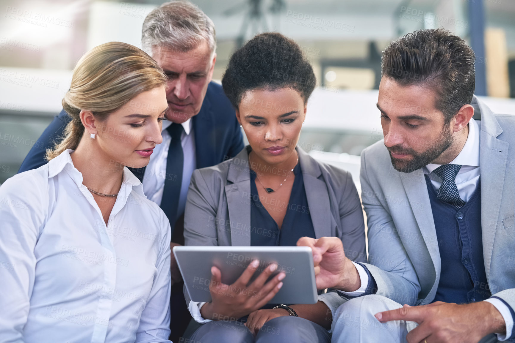 Buy stock photo Cropped shot of a group of businesspeople working together on a digital tablet in an office