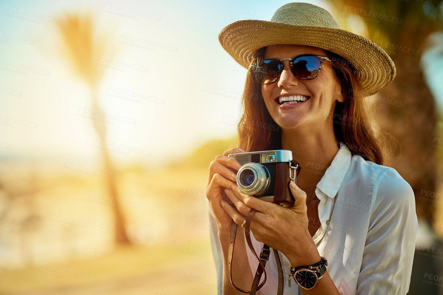 Buy stock photo Shot of an attractive young woman using a camera on a summer’s day outdoors