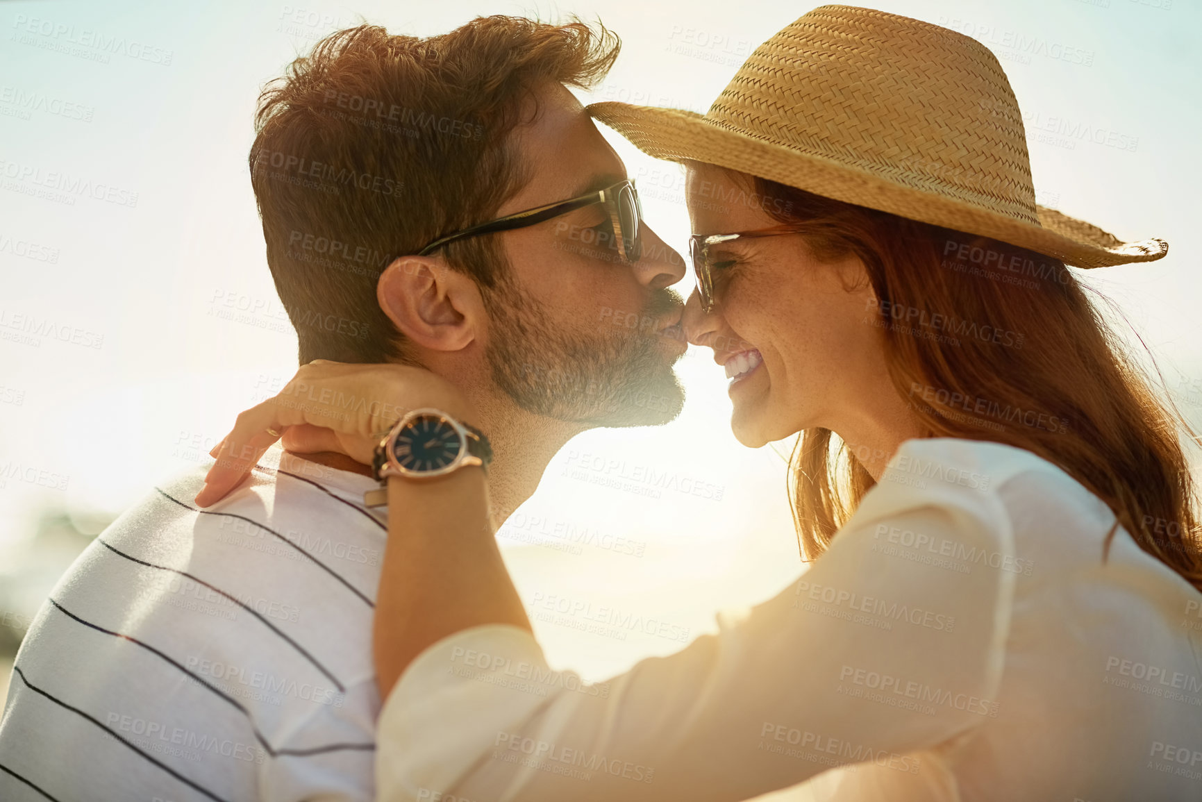 Buy stock photo Shot of a young man kissing his girlfriend’s nose on a summer’s day outdoors