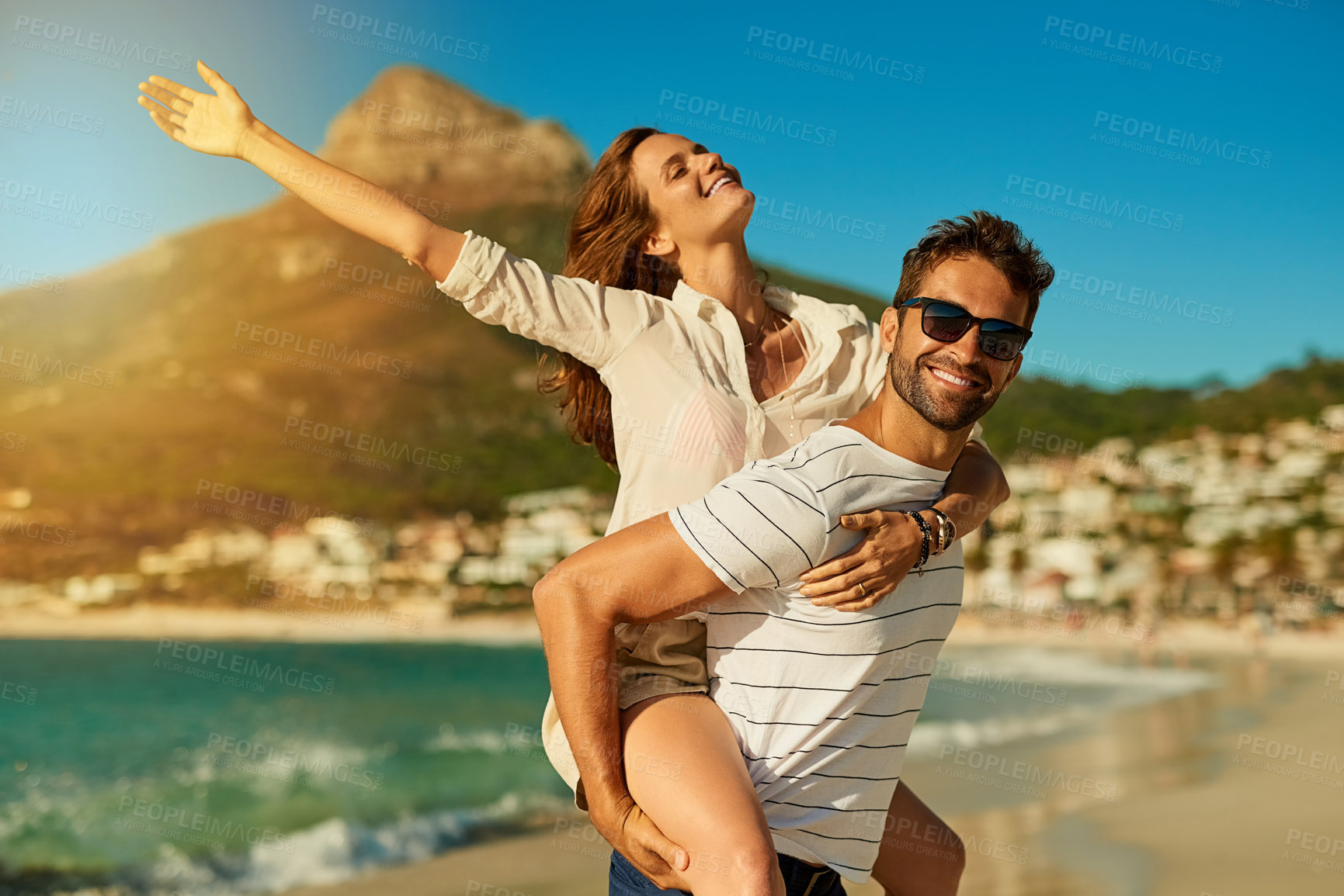 Buy stock photo Portrait, couple and piggyback on beach for love, commitment and bonding on summer vacation for honeymoon. Man, woman and freedom by ocean for romantic holiday, affection and weekend with embrace.