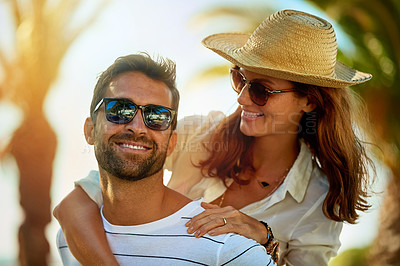 Buy stock photo Shot of a happy young couple enjoying a piggyback ride at on a summer's day outdoors