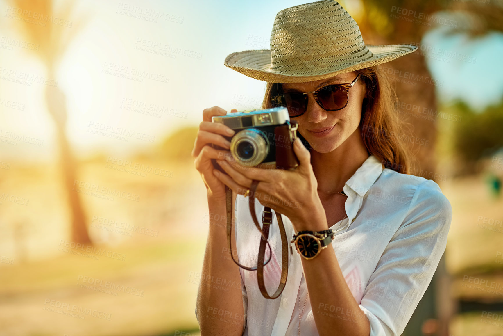 Buy stock photo Shot of an attractive young woman using a camera on a summer’s day outdoors