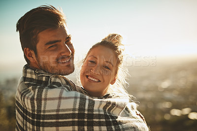 Buy stock photo Shot of an affectionate couple wrapped in a blanket while spending time out in nature