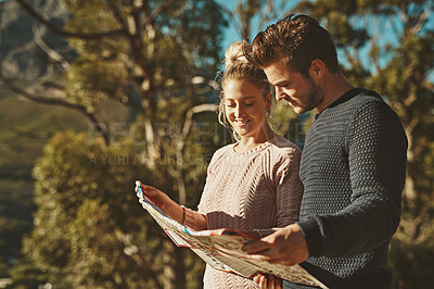 Buy stock photo Shot of a young couple looking at a map while out hiking