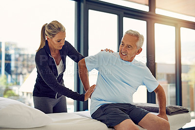 Buy stock photo Shot of a physiotherapist examining a senior patient with back pain in her office
