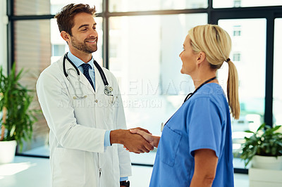 Buy stock photo Shot of two healthcare practitioners shaking hands in the hospital foyer