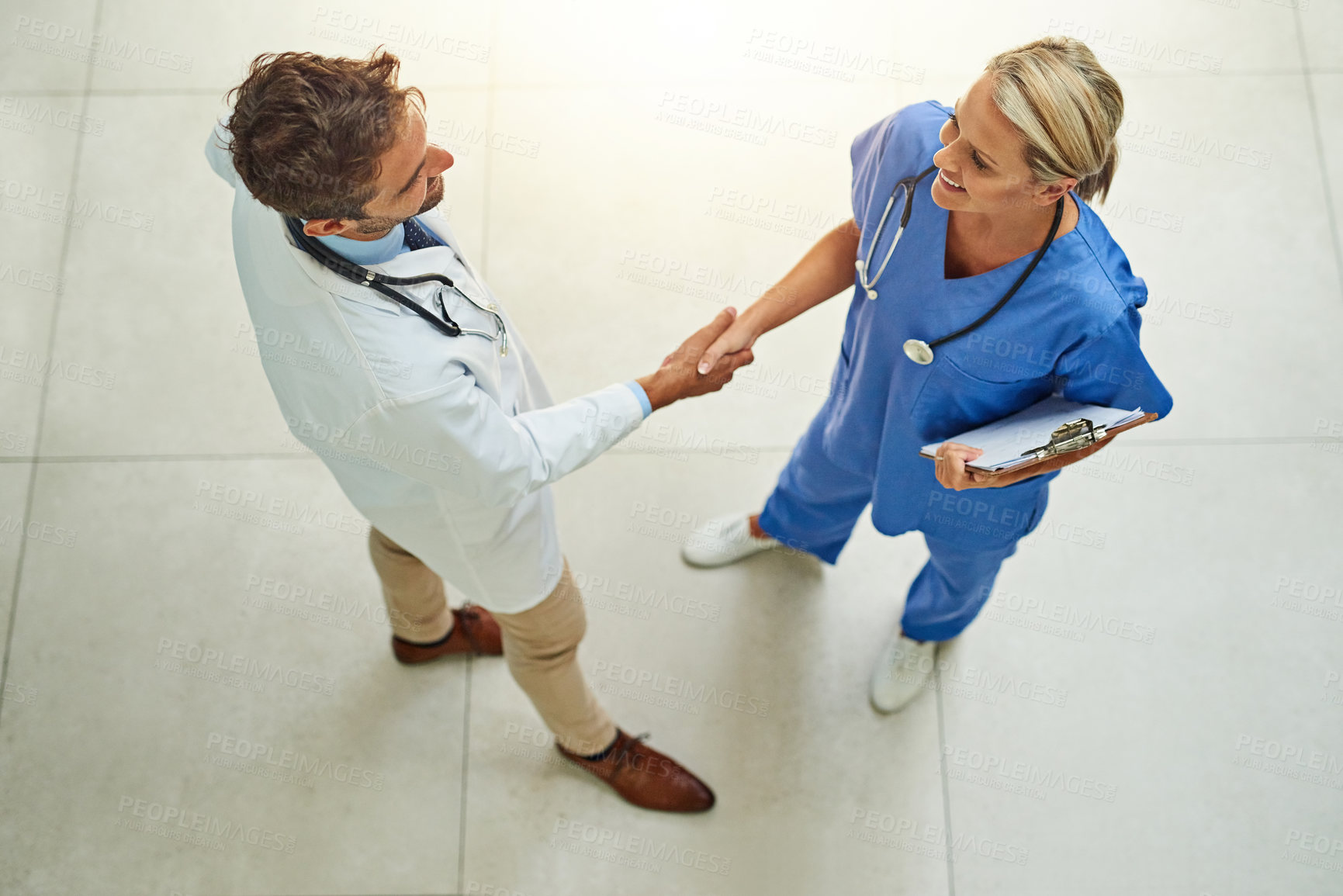 Buy stock photo High angle shot of two healthcare practitioners shaking hands in the hospital foyer
