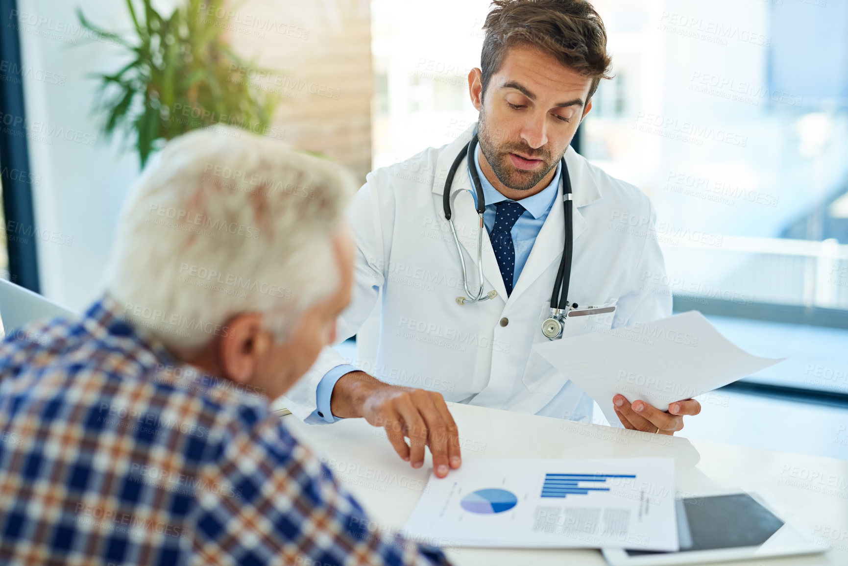 Buy stock photo Shot of a doctor consulting with a patient at his desk